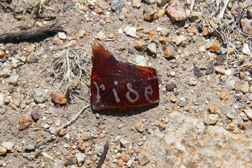 On our way back to the truck we find a fragment of glass with something etched into it.