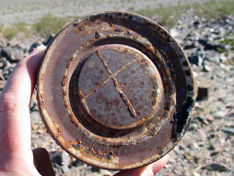 A hole and cap can with a unique "x" marked in solder on the cap.