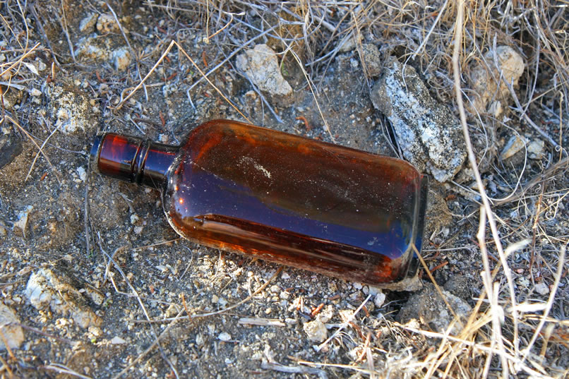 Niki also spots a glint of light on the hillside above the wash and climbs up to investigate.  It looks like a spirits bottle.