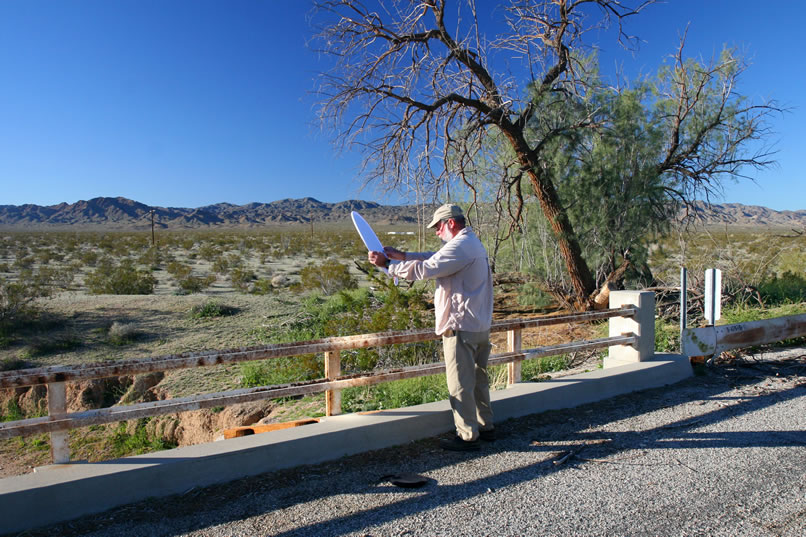 When we meet Mohave at Chiriaco Summit, he suggests taking the old Shavers Well road back toward the southern park entrance so he can show us these bridge rails made of old railroad tracks.  Here he holds our reflector to try to highlight the date stamped on the rail.