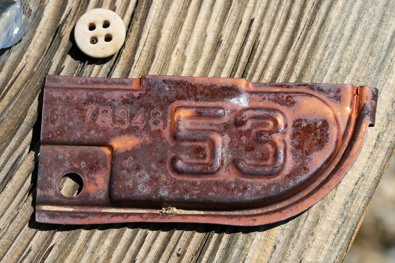 Nearby we find a 1953 license plate tag and a button.