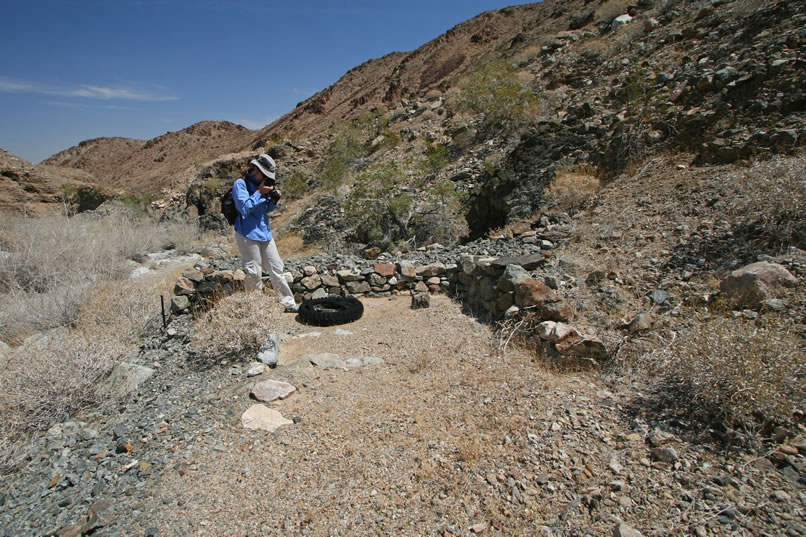 Again, we find a small rock edged flat spot where another tent cabin likely stood.  The dark opening of the tunnel can just be seen behind the clearing.