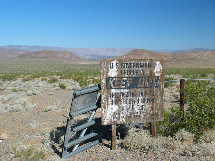 The metal gate, identified by a sign as the Davis Gate, has been ripped from its hinges and rests against the fence line.