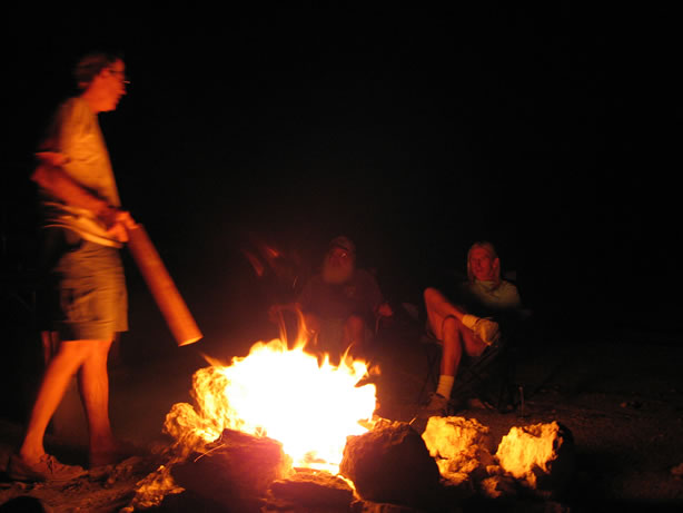 Bob adds wood to the fire as Roms and Allan supervise.