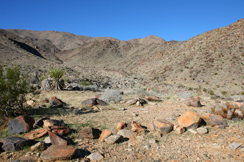 Even before we enter the hills that you can see in the background, we're surprised to find the faint remains of what appears to have been an old miner's camp.  Here you can see the unmistakable rock outline of a tent cabin site.