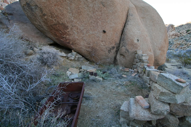 Most of the stacked stone wall is still in place.  Just above it, where it meets the boulder, you can see a square notch carved into the boulder, almost as if a support beam once fit there.