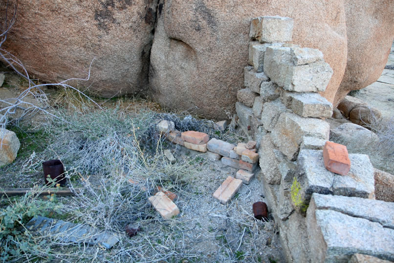 A small fireplace area, which may or may not be original, has been constructed in the corner of where the wall meets the boulder.