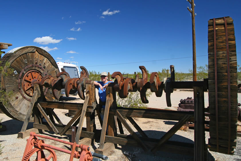 Alysia poses between two banks of lifting cams for a ten stamp mill.