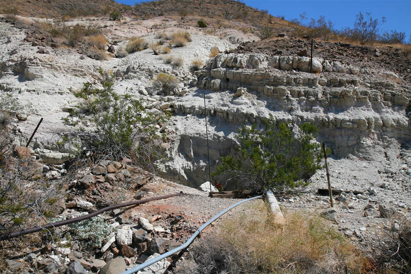 The pipes disappear down a timbered shaft next to the cliff face.