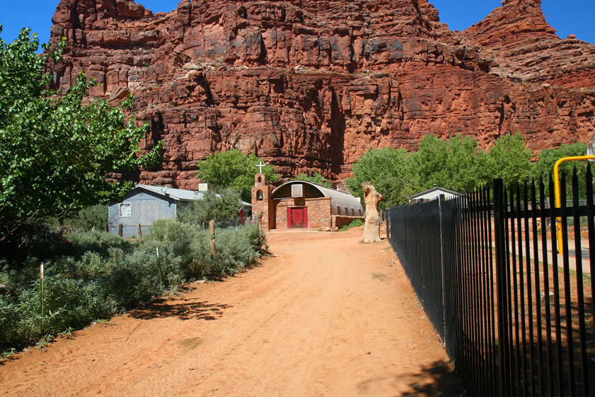 A quick stop at the Tourist Office is made to pick up our permits.  It feels good to get those packs off!  We also quickly check out the village store and the cafe before continuing on down toward the campground.  The fence on the right is in front of the school and the church is straight ahead.  Only two more miles!