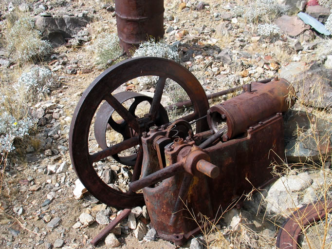 A larger single cylinder engine with the remains of the other flywheel lying broken beside it.