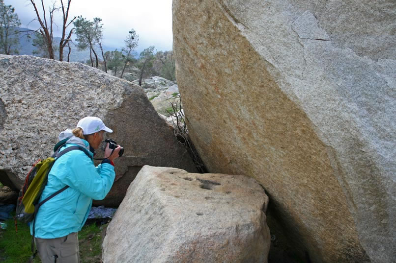 Nearby, Jamie photographs the flat rock with ceremonial cupules that lies below the almost vertical boulder face which contains the pictograph.