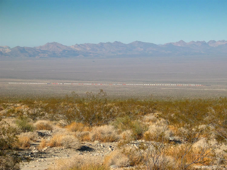 Behind us a colorful freight train crawls eastward across the desert floor.