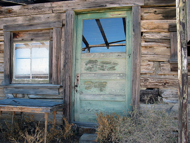 The front door with a view of the porch beams reflected in the window glass.