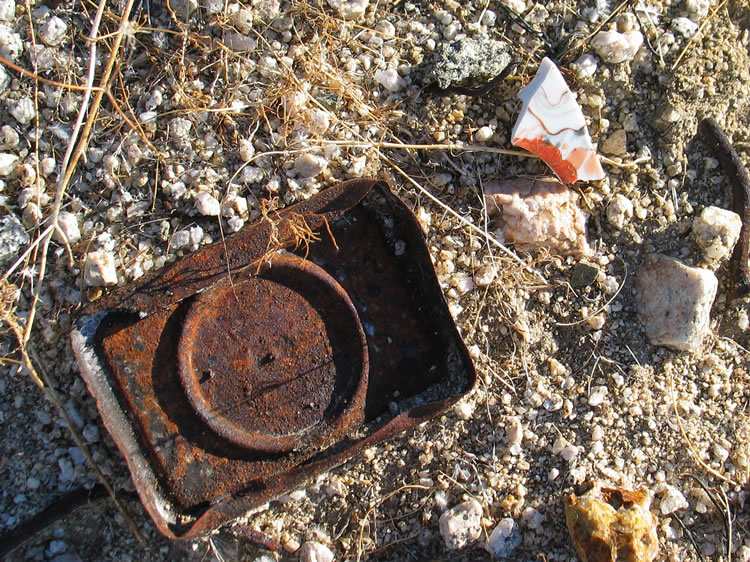 The top of a hole and cap tin and a pottery fragment.