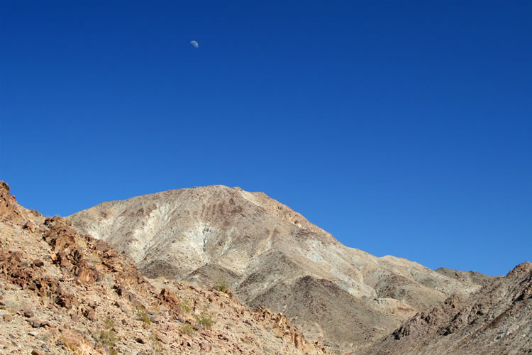 The moon hanging above the colorful hills makes for a nice photo opportunity.