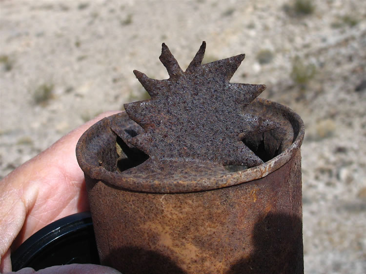 In the lower part of the cairn is a tin can with a very distinctive pattern cut into its lid.  Shaking the can hints that there's something inside.