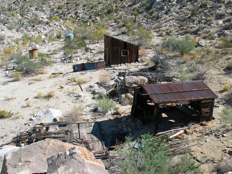 This view from above shows part of the large foundation to the left, what appears to be a workshop and stable to its right, another foundation ruin behind these two and then a small cabin.  Beyond that is a water tank and the rock foundation of the outhouse which is hidden in this shot.