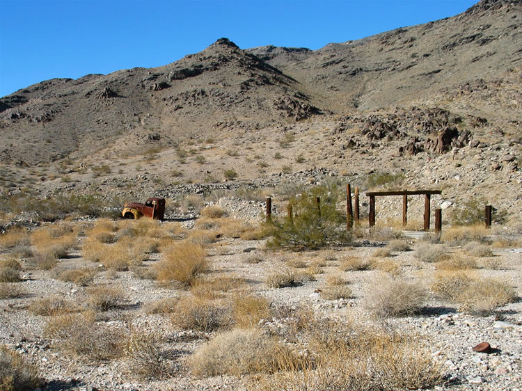 Across from the cabin site is a colorful old truck cab and a long cement pad with a few railroad tie posts and beams still standing.  Wood planks and asphalt shingles hint that at one time at least part of the cement pad was enclosed.