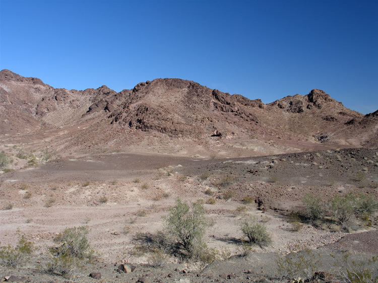 Can you see the black slit of the shelter just above the interesting old trail that runs across the base of the hill to the north of our location?