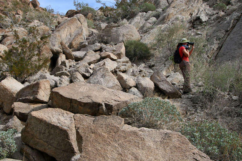 Just behind her, on the top of a flat boulder, are two petros that she points out before she gets back to photographing the panel that brought her over there in the first place.