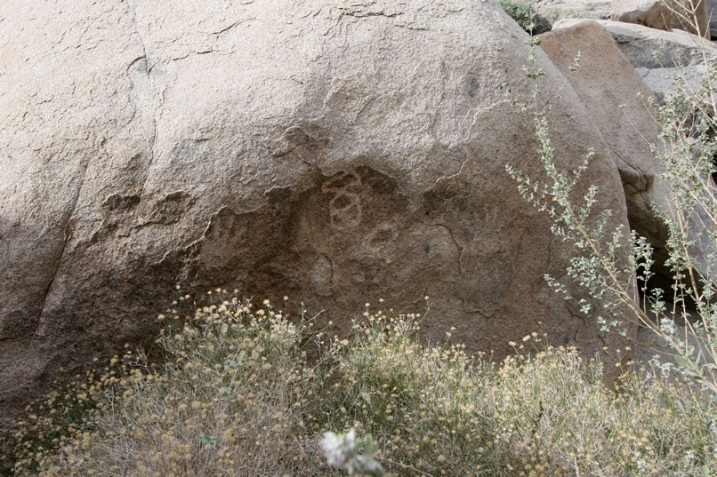 On this boulder, a central image is flanked by two hand prints.