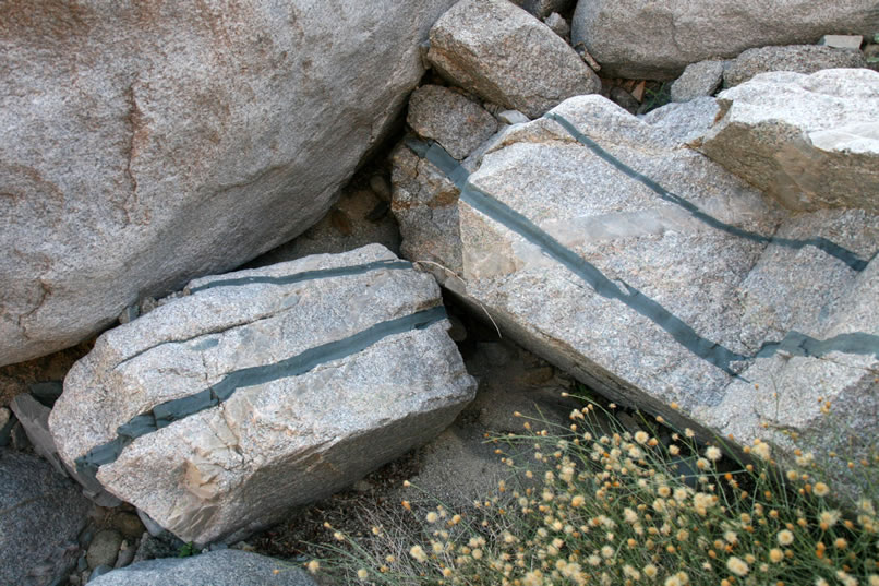 She passes a couple of boulders striped with colorful blue-green veins.