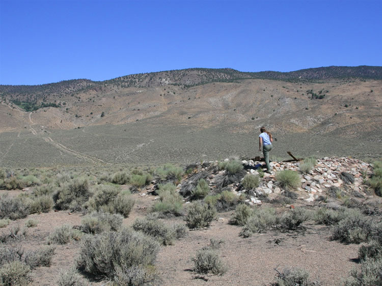 Niki climbs up a low mound-like structure with interior timbering.  Surrounding this site are expansive can dumps all out of proportion to what one would expect in such a barren area.