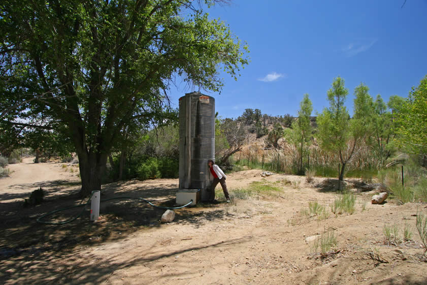 Vaughn Spring, like all of the springs that we've visited today, is flowing well.  The storage tank next to Niki is overflowing from the top and there's a small pond nearby.