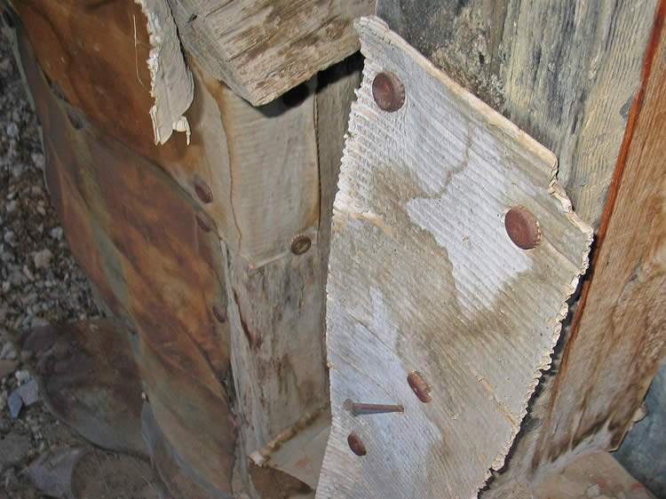 The inside walls are covered in what appears to be old cardboard boxes and the same nail and bottle cap method is used to attach the material to the wood frames.