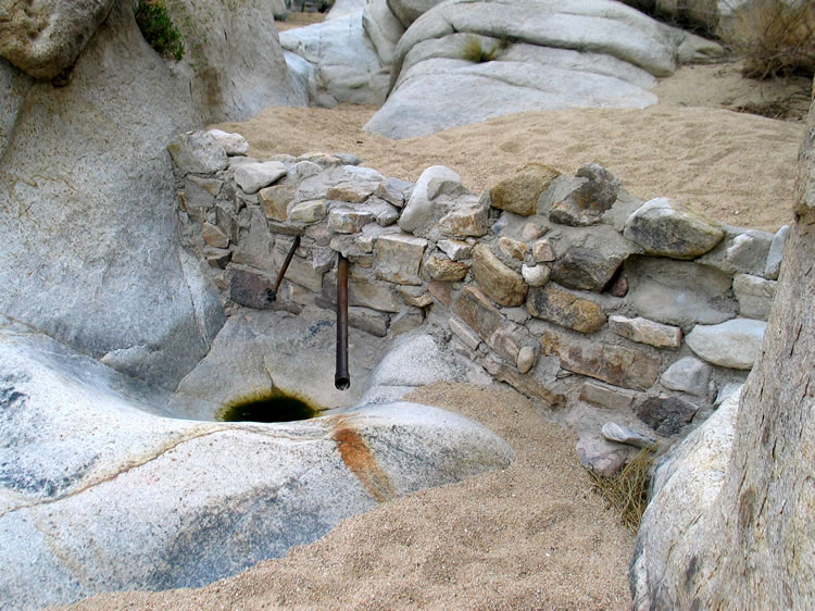 There's a spring in the area that was most certainly used by the Indians before the ranchers built this check dam and installed the pipes.  The granite tank would have appealed to the earlier Indians.