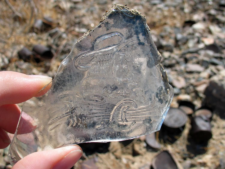 This glass fragment has what appears to be the image of a Quaker above a sheaf of wheat.