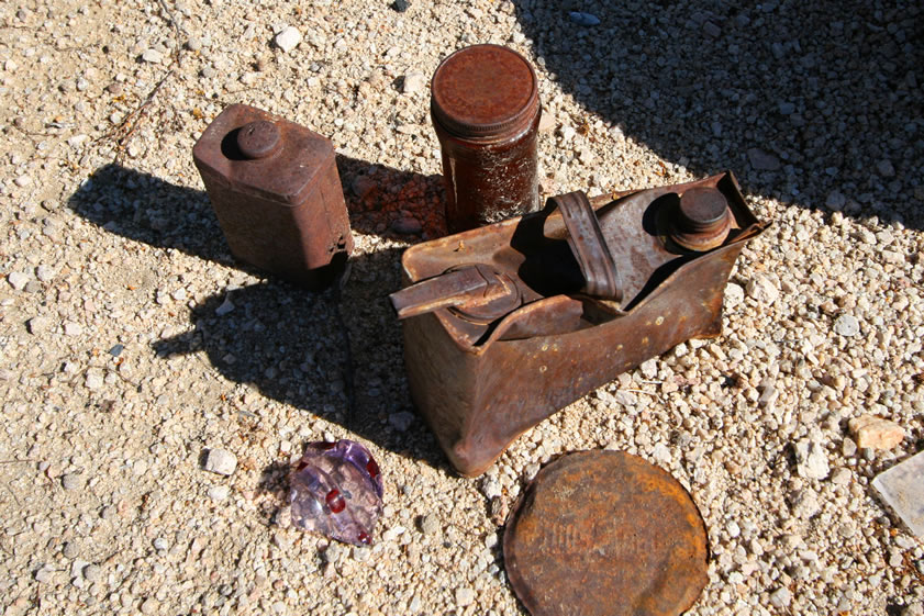 In this closer view you can see a talcum powder or tooth powder tin, an intact jar, a neat little oil can, the embossed lid to a coffee can and a colorful glass fragment.