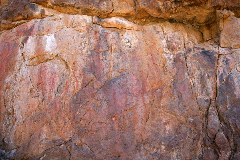 This view is of an area of the rock face that is to the right of the previous photos.  Again, close scrutiny will uncover numerous red pictographs.  Many of them, however, are smudged or have been painted over so it's tough to get a clear view.  Roll your mouse over the photo for an enhanced view.