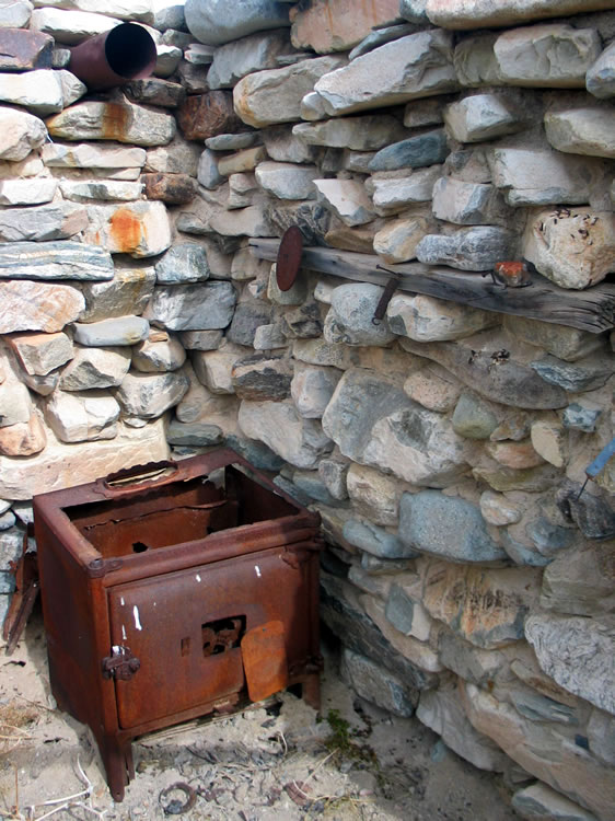 Notice the stove pipe exiting through the wall above the stove.  Also, the handy wood shelf is a nice touch.