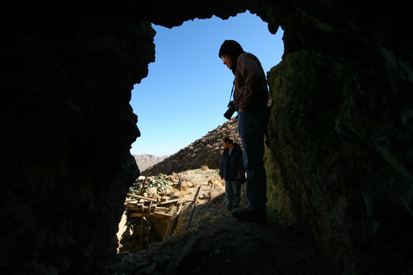 Guy, with Alysia behind him,  looks down into the shaft from the entrance to the mine.