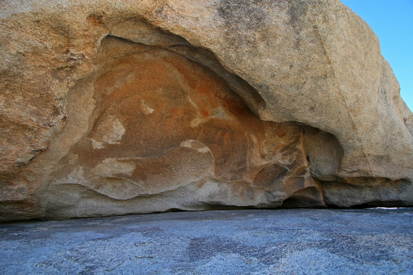 Under the overhang of a weathered niche in a large boulder is a small pictograph panel.