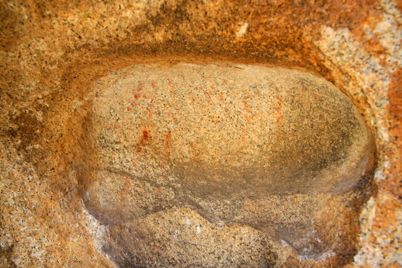 In a small hollow on a nearby boulder are a few more faint red pictographs.