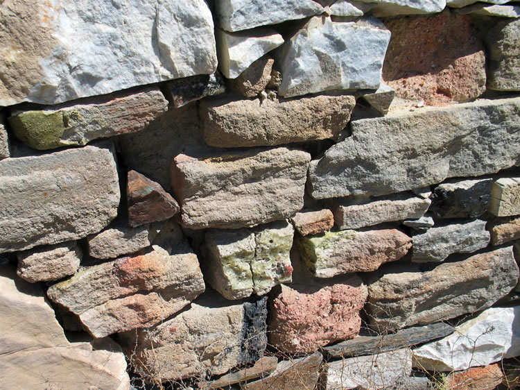 Some of the stones used in the walls look as if they were at one time part of a furnace due to the light greenish coating of slag found on them.