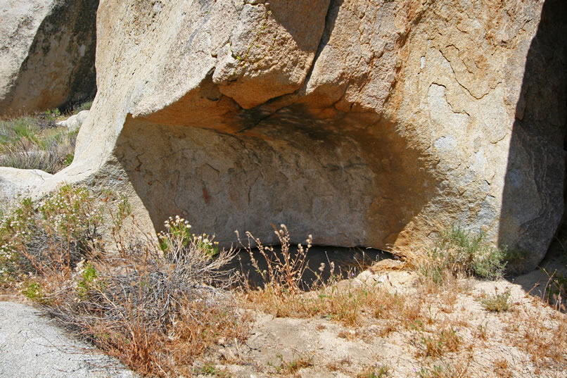 Nearby is a small shelter that has a couple of small vertical red picto lines as well as an element in black off to the right side of the opening.