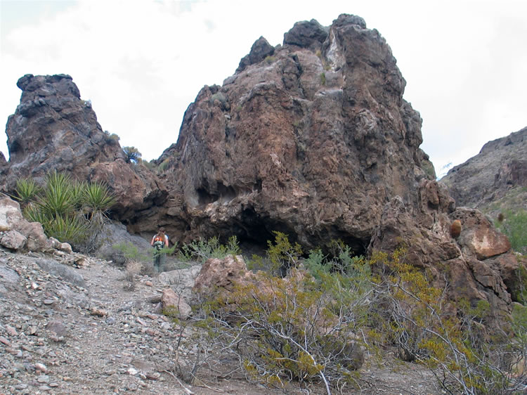 Niki follows a faint trail that lifts out of the wash and leads toward a large rock shelter.