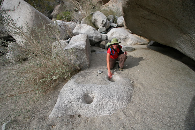 In a sandy alcove is a low boulder with two grinding holes.