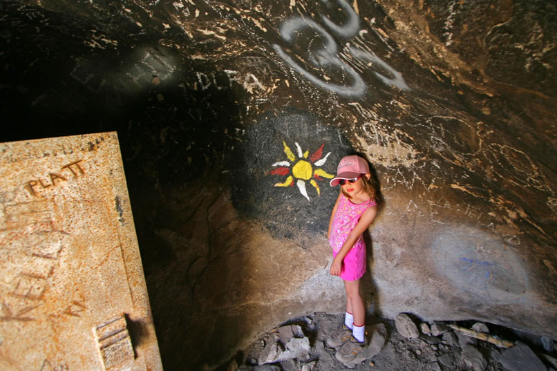 Matt's daughter, Kirsten, poses with some of the graffiti that now adorns the walls and ceiling of this hollow boulder.