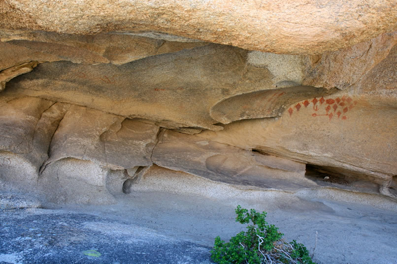 The site consists of two separate individual elements to the left, then a net-like panel in a hollow portion of the rock wall and then further to the right the very distinctive red diamond pattern.