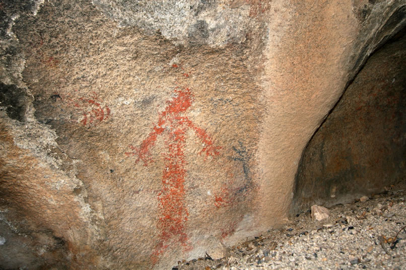 In the case of this shelter, formed by two leaning boulders , it's not the pictograph that interacts with the piercing rays of the sun to mark the beginning of spring.  Rather, the pictograph seems to be a more recent addition, possibly of Chemehuevi origin, that looks on at the nearby bedrock mortar of much older construction, possibly Maringayam, which acts as the vaginal "cave" that is pierced by the arrow of the sun on the first day of spring.