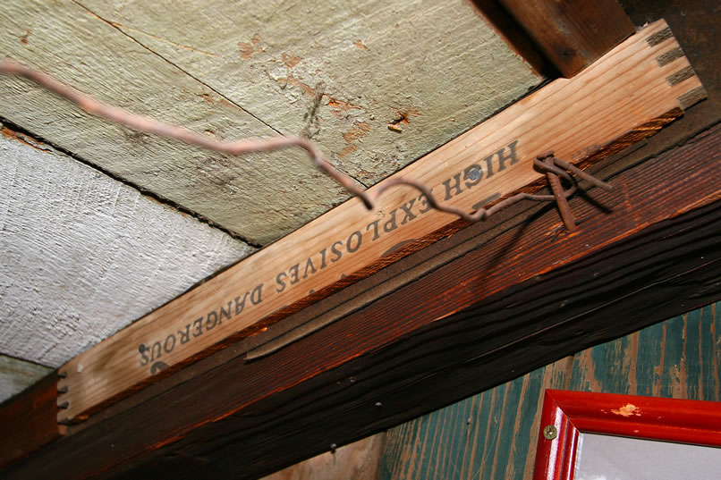 Parts of old dynamite boxes are used to hold the cabin's ceiling planks in place.