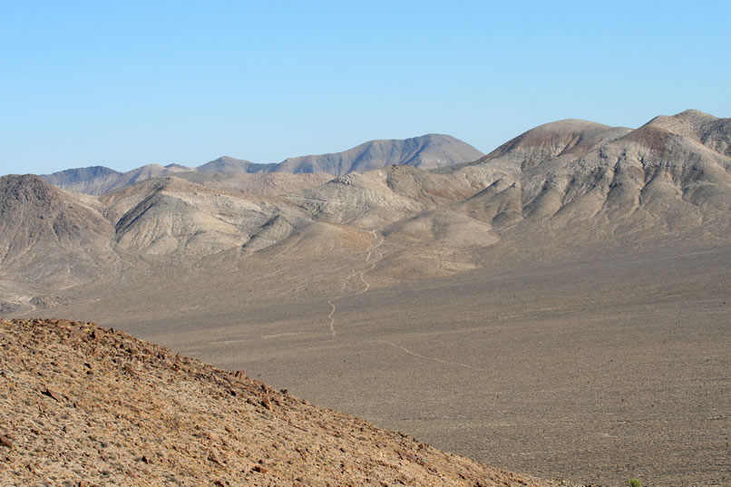 As we descend, we get a view across Ulida Flat to the little thread of a road that will lead us up to the Ubehebe Talc Mine where we'll camp tonight.